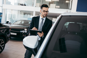 Poster - Car seller working in showroom and quality control checking of car details for the last time before buyer comes.