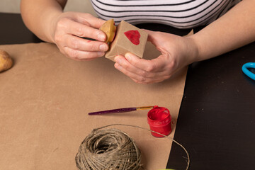 Wall Mural - heart shaped potato stamp on craft paper. The process of decorating a gift for Valentine's Day. Getting ready for the celebration on February 14th.