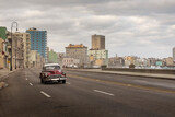 Fototapeta  - Old car on Malecon street of Havana with storm clouds in background. Cuba