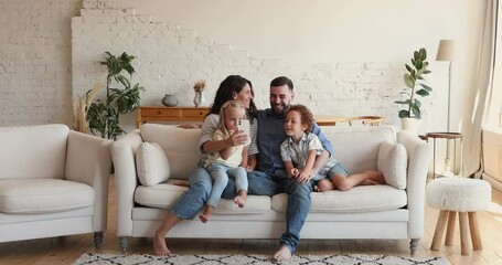 Wall Mural - Smiling happy family with children sit on sofa in living room have fun use modern smartphone looking at screen making selfie, enjoy new mobile app spend carefree weekend at home. Wireless tech concept