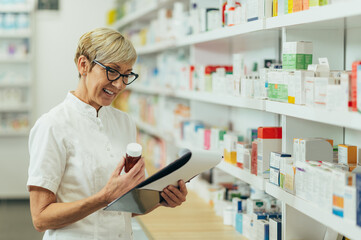 Beautiful senior female pharmacist checking medications on a shelf