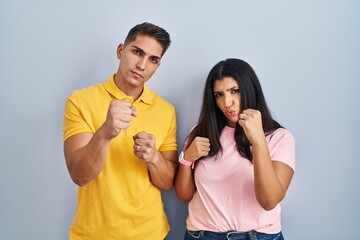 Canvas Print - Young couple standing over isolated background ready to fight with fist defense gesture, angry and upset face, afraid of problem