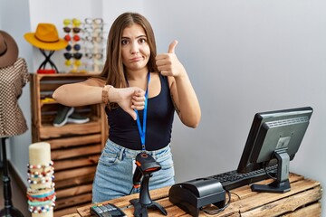 Sticker - Young brunette woman holding banner with open text at retail shop doing thumbs up and down, disagreement and agreement expression. crazy conflict