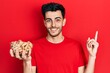 © Krakenimages.com - Young hispanic man holding peanuts smiling happy pointing with hand and finger to the side