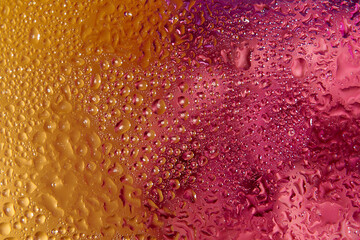 Blurred purple and gold background with lots of water drops. Closeup.