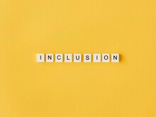 Inclusion Word Written Scrabble Letters Yellow Background. High Quality Photo