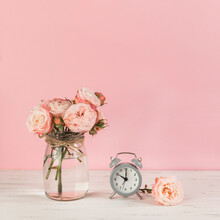 Roses Vase Near Alarm Clock Wooden Desk Against Pink Background. High Quality Photo