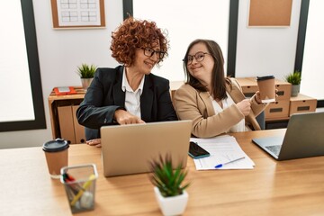 Wall Mural - Group of two women working at the office. Mature woman and down syndrome girl working at inclusive teamwork.