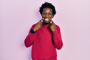 Poster - Young african american man wearing casual clothes smiling with open mouth, fingers pointing and forcing cheerful smile