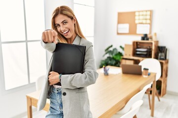 Wall Mural - Blonde business woman at the office pointing to you and the camera with fingers, smiling positive and cheerful