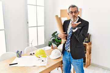 Poster - Middle age hispanic business man holding paper blueprints looking at the camera blowing a kiss with hand on air being lovely and sexy. love expression.