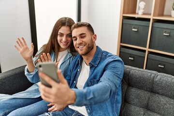 Sticker - Young caucasian couple having video call using smartphone at home.