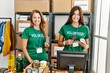 © Krakenimages.com - Mother and daughter wearing volunteer uniform scanning food using barcode reader at charity center