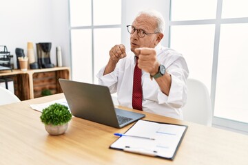 Canvas Print - Senior man working at the office using computer laptop ready to fight with fist defense gesture, angry and upset face, afraid of problem