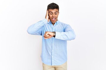 Poster - Young hispanic man wearing business shirt standing over isolated background looking at the watch time worried, afraid of getting late