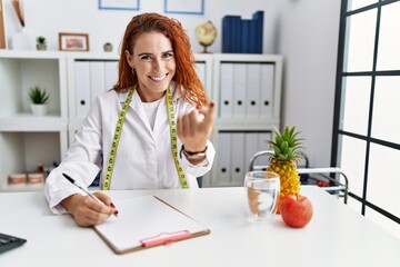 Poster - Young redhead woman nutritionist doctor at the clinic beckoning come here gesture with hand inviting welcoming happy and smiling