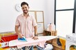 Young man with beard ironing clothes at home sticking tongue out happy with funny expression. emotion concept.