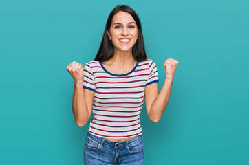 Young hispanic girl wearing casual striped t shirt celebrating surprised and amazed for success with arms raised and open eyes. winner concept.