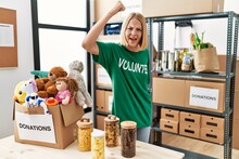 Young Caucasian Woman Wearing Volunteer T Shirt At Donations Stand Angry And Mad Raising Fist Frustrated And Furious While Shouting With Anger. Rage And Aggressive Concept.