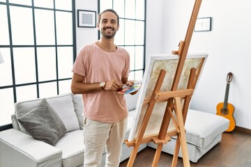 Wall Mural - Young hispanic man with beard painting on canvas at home with a happy and cool smile on face. lucky person.