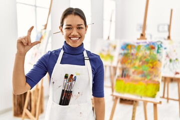 Sticker - Young brunette woman at art studio smiling and confident gesturing with hand doing small size sign with fingers looking and the camera. measure concept.