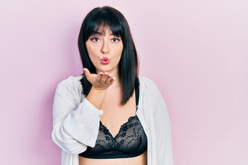 Poster - Young hispanic woman wearing lingerie looking at the camera blowing a kiss with hand on air being lovely and sexy. love expression.