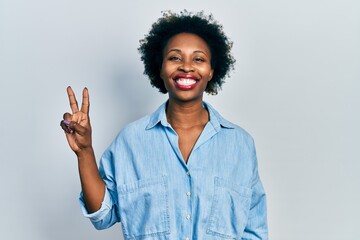 Wall Mural - Young african american woman wearing casual clothes smiling with happy face winking at the camera doing victory sign. number two.