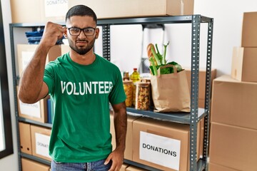 Canvas Print - Young indian man volunteer holding donations box angry and mad raising fist frustrated and furious while shouting with anger. rage and aggressive concept.