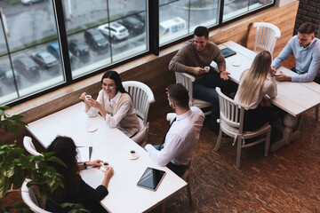 Canvas Print - Coworkers having coffee break near window in cafe, above view