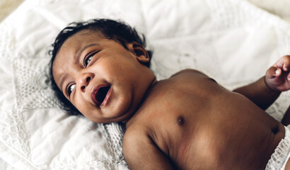 Wall Mural - Portrait of cute adorable little african american baby looking at camara in a white bedroom