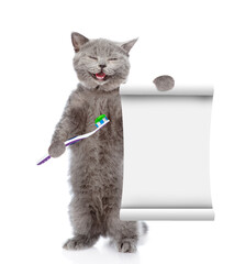 Poster - Happy kitten holds toothbrush and shows empty list. isolated on white background