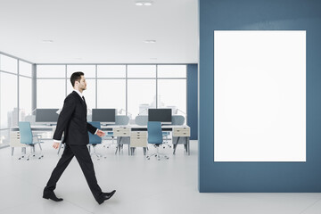 Aufkleber - Businessman walking in modern concrete coworking office room interior with panoramic window with city view, empty white mock up poster frame, equipment, daylight and furniture.