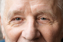 Close Up Portrait Of Old Smiling Man Looking At Camera. He Is Open-eyed And Cheerful. Smiling Blue Eyes Of A Happy Senior Man 