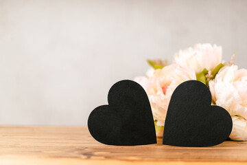 Still life pink Valentines day festive background with empty 2 black chalkboard heart and flowers on wooden table. Mockup with copy space for design. 