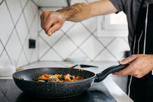 Man Sprinkling Salt On Vegetables In Frying Pan