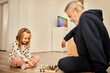© Westend61 - Granddaughter and grandfather playing chess at home