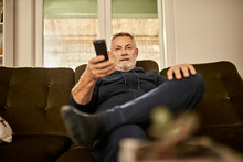 Senior Man With Remote Control Watching TV At Home