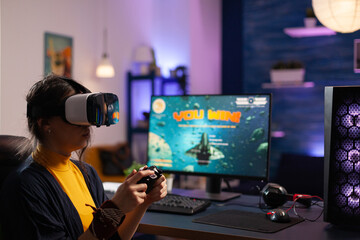 Wall Mural - Woman winning video games with vr glasses on computer. Gamer playing with virtual reality headset and controller to win online game on monitor. Player with modern equipment at desk.