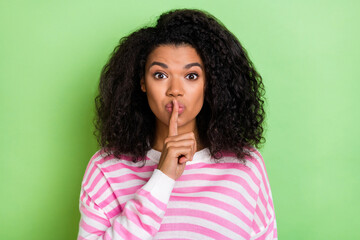 Wall Mural - Portrait of attractive cute brunet girl showing shh sign keep silence isolated over bright green color background