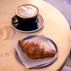 A mug of latte coffee with Croissant coffee break on wooden table