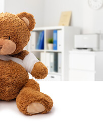 Wall Mural - medicine, healthcare and childhood concept - teddy bear toy with bandaged paw over medical office at hospital background