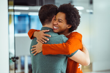 Laughing african-american, giving a supportive hug to her employee.