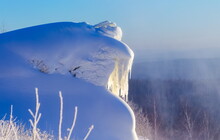 A Snowdrift With Icicles On The Mountainside Against The Blue Sky In Winter