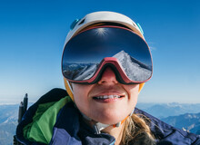 High Altitude Mountaineer Smiling Female Portrait In Safe Ski Helmet And Goggles On The Mont Blanc 4810m With Picturesque Alpine Mountains Background. Active Sporty People And Success Concept Image