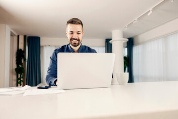 Wall Mural - a focused entrepreneur working online on laptop from home and smiling.home, apartment, house, bright
