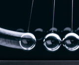 Fototapeta  - nahaufnahme von 3 kugeln eines newton-pendels in Aktion vor dunklem hintergrund