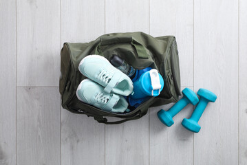 Wall Mural - Sports bag with gym stuff and equipment on white floor, flat lay