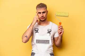 Young painter man isolated on yellow background pointing temple with finger, thinking, focused on a task.