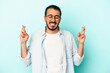 © Asier - Young caucasian man isolated on blue background crossing fingers for having luck