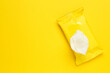 Wet wipes flow pack on yellow background, top view. Space for text